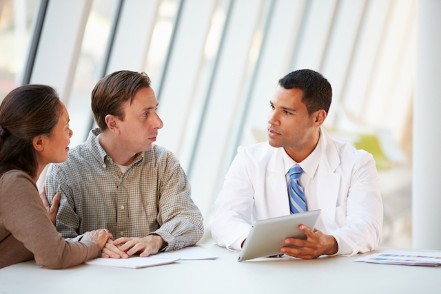 A doctor using a tablet computer in a patient's discussion