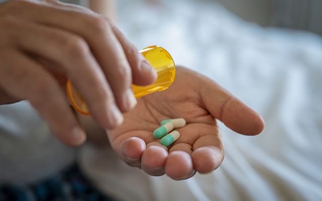 A patient pouring pills into their hands