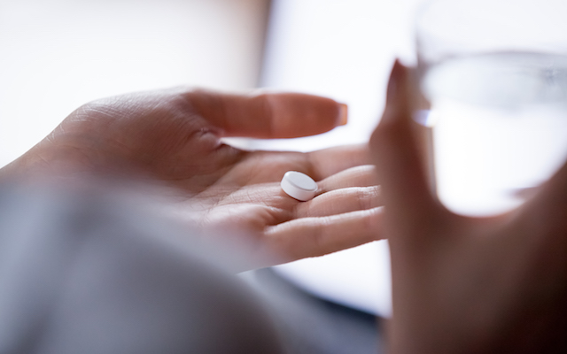 Close up woman holding pill in hand with water. Female going to take tablet from headache, painkiller, medication drinking clear water from glass. Healthcare, medicine, treatment, therapy concept
