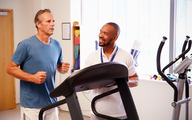 Man running on treadmill in medical setting.