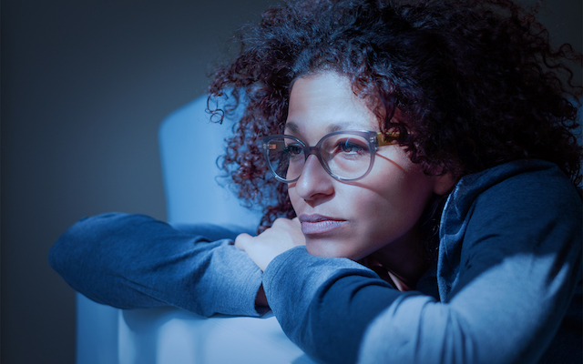 Woman lying on sofa at night.
