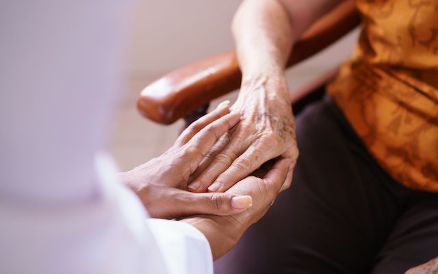 Closeup of a physician holding an older person's hand