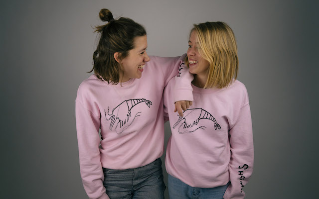 Char and Madi Kennedy smile at each other wearing one of their clothing designs
