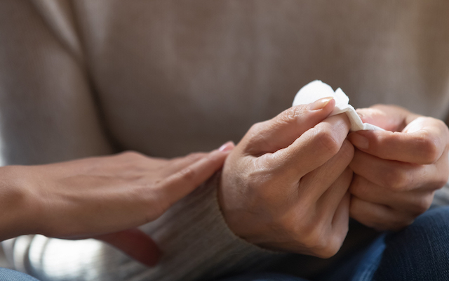 Close-up of hands holding a tissue.