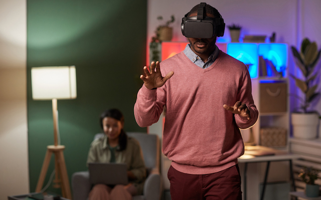 A man wears a VR headset, monitored by a researcher.