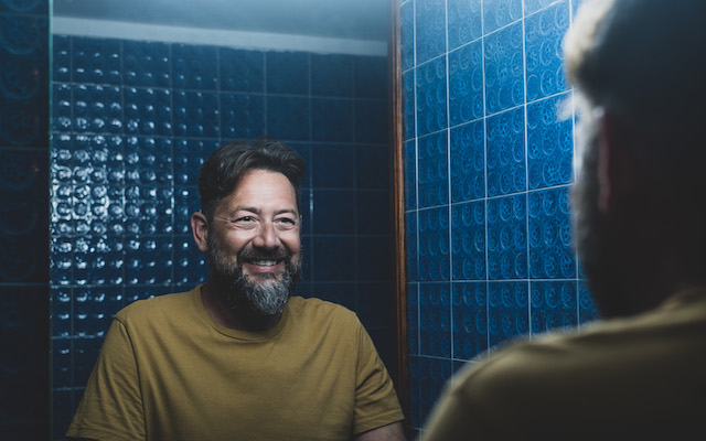 A man smiles in the mirror.