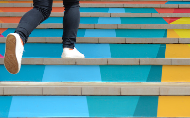 A person runs up colourful stairs.