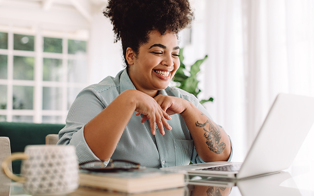 Positive woman video calling using laptop. Businesswoman teleconferencing on laptop while working from home.