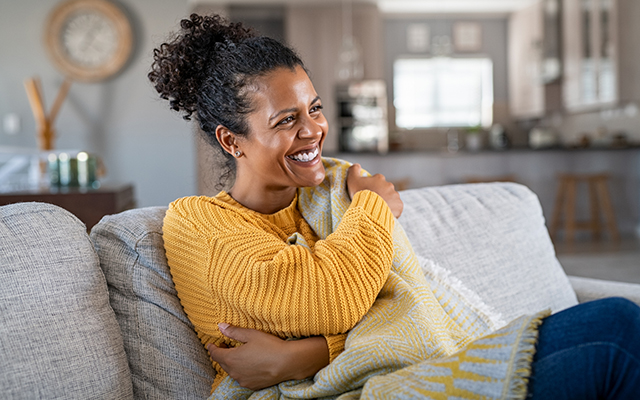 A woman hugs herself, smiling.
