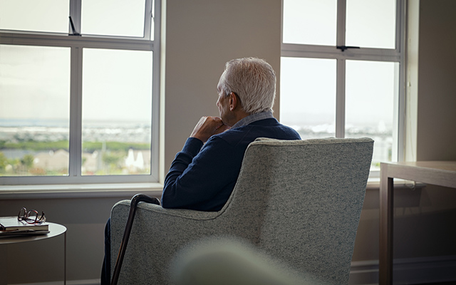 Lonely senior man looking outside the window