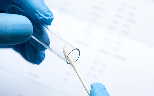 Doctor holds a COVID-19 swab collection, wears blue gloves and a PPE protective mask, and carries a test tube to collect the OP NP and test coronavirus.
