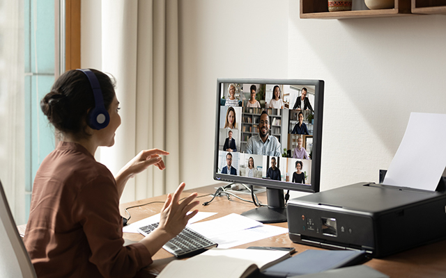 Smiling Indian woman sit at desk at home office talk speak on video call with multiethnic diverse colleagues. Ethnic female employee have webcam digital virtual event on computer with businesspeople.