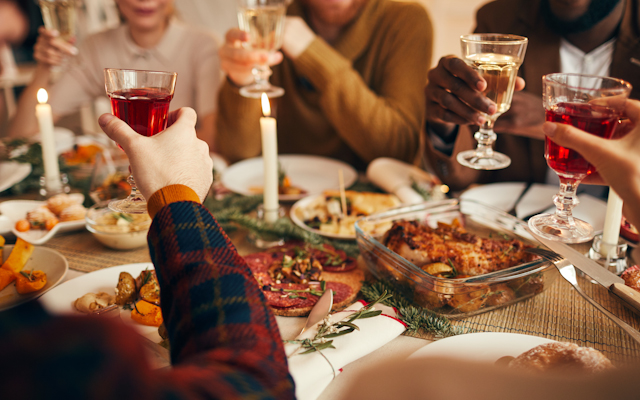 Closeup of a Christmas meal with people holding up wine glasses
