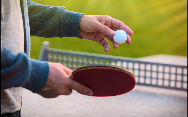 Close up of hands holding a ping pong racket and a ball