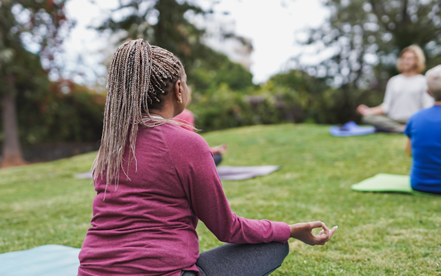 A woman meditating outdoors.