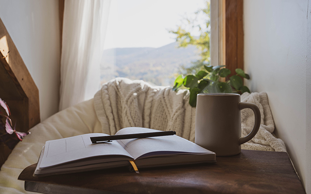A cozy mental health break with an open journal, pen and coffee cup.