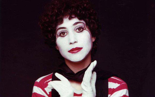 A close up of Barbara Salsberg Mathews striking a pose with her face painted white