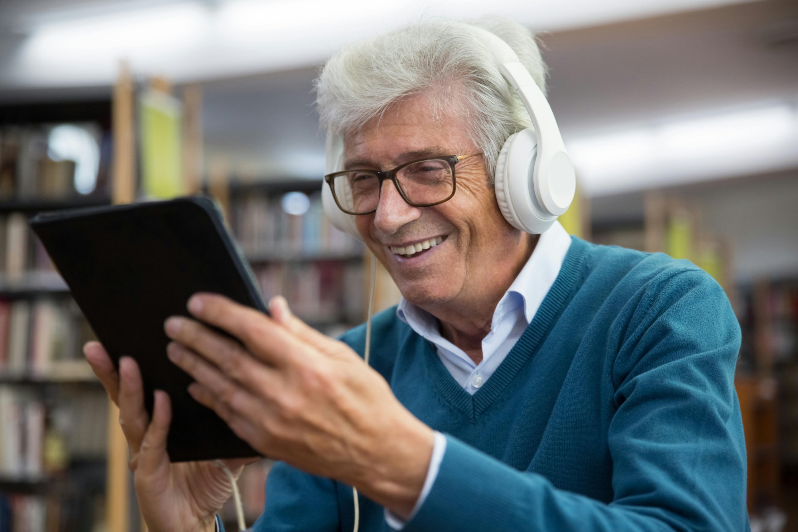 Man smiling while holding a tablet and wearing headphones