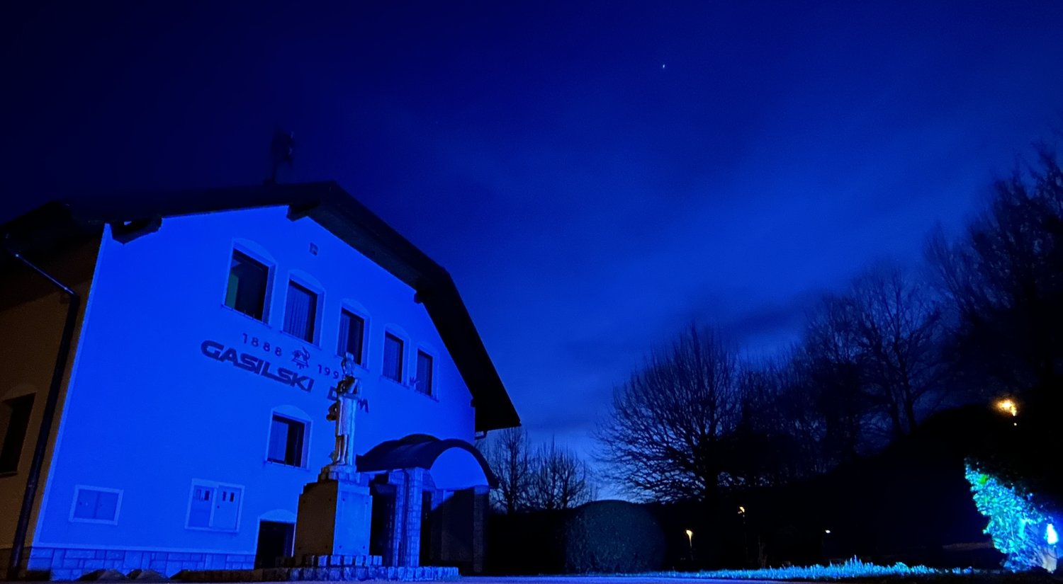 A photo of a World Parkinson's Day event in Slovenia, featuring the old fire house lit up in blue for Spark the Night