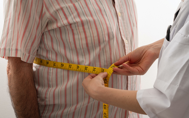 female doctor is measuring senior man's body circumference