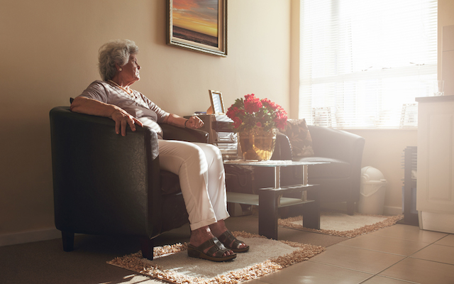 Senior woman sitting alone on a chair at home