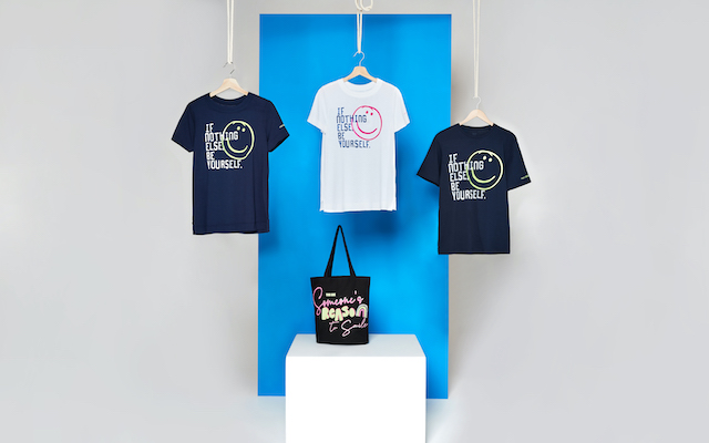 Three t-shirts and a tote bag are displayed against a blue backdrop.