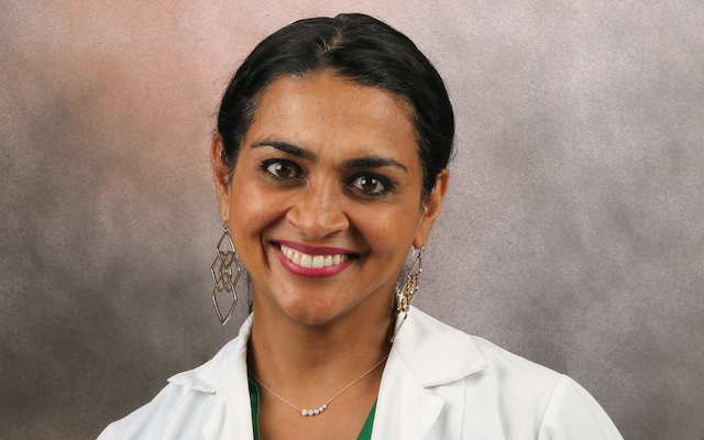 Dr Indu Subramanian smiles for a portrait in a lab coat.