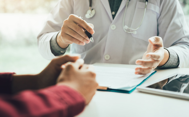 A patient and doctor converse over files.