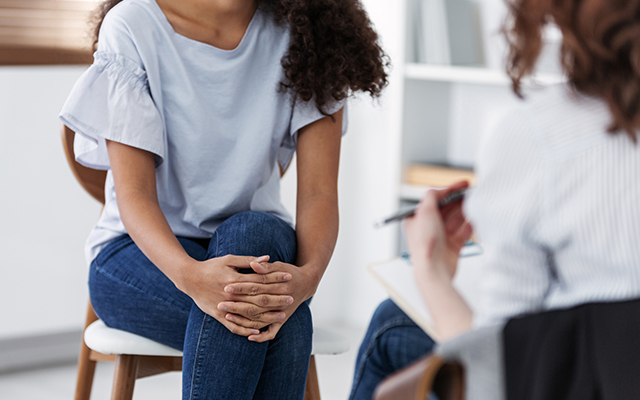 A woman sits with a therapist.
