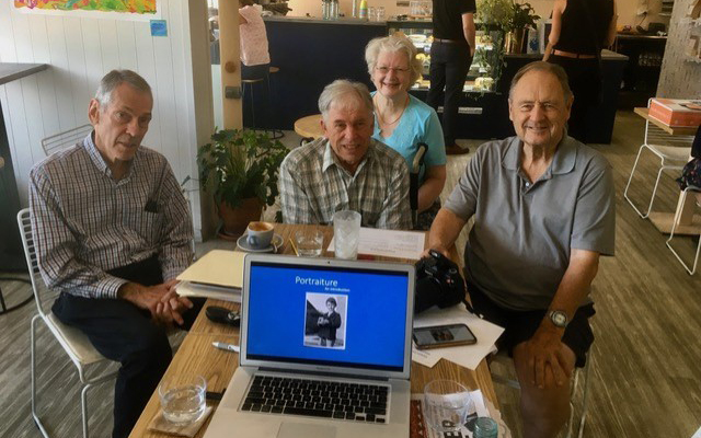 The group share coffee and discuss their photos in a café