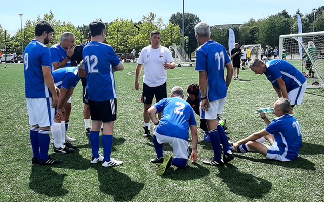 The walking football team standing on the pitch talking to each other