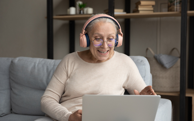 Woman sitting down on a chair wearing headphones while on her laptop