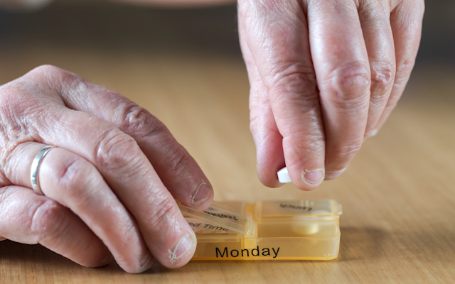 A pair of hands holding a pill box.